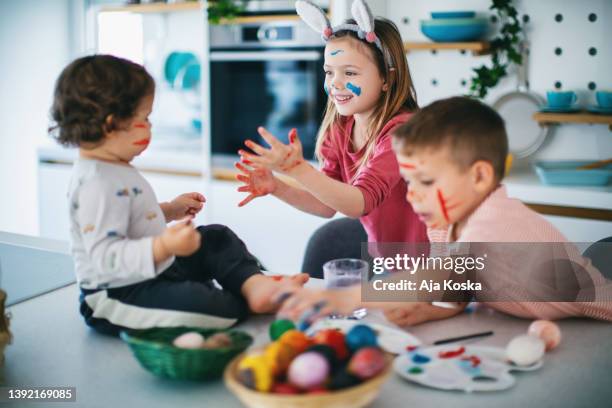 siblings painting easter eggs together. - dirty easter stock pictures, royalty-free photos & images