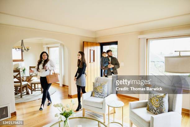 wide shot of family walking into home for sale with real estate agent - couple real life stockfoto's en -beelden