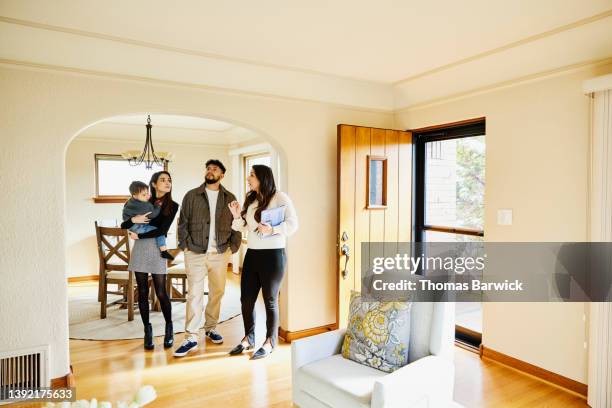 wide shot of family looking at home for sale with real estate agent - visita de inmuebles en venta fotografías e imágenes de stock