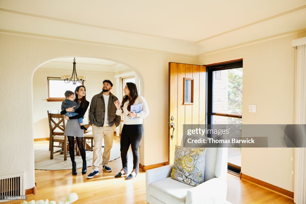 Wide shot of family looking at home for sale with real estate agent