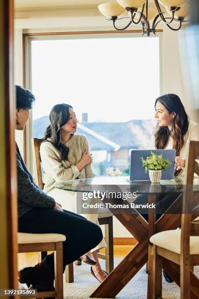 medium wide shot of couple in discussion with real estate agent - luxury home dining table people lifestyle photography people stock pictures, royalty-free photos & images