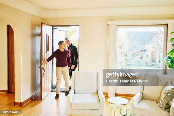 wide shot of gay couple walking into home for sale during open house - purple coat fotografías e imágenes de stock