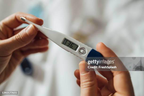 a close up shot of an unrecognizable woman measuring her temperature during coronavirus recovery - termometer bildbanksfoton och bilder