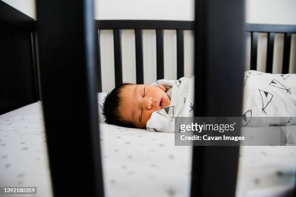 newborn baby sleeps soundly in his crib - babydecke stock-fotos und bilder