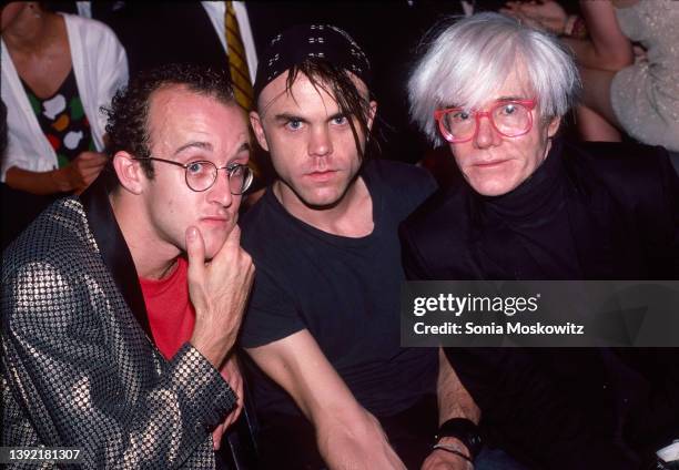 Portrait of, from left, artist Keith Haring , fashion designer Stephen Sprouse , and Pop artist Andy Warhol as they sit together during a fashion...