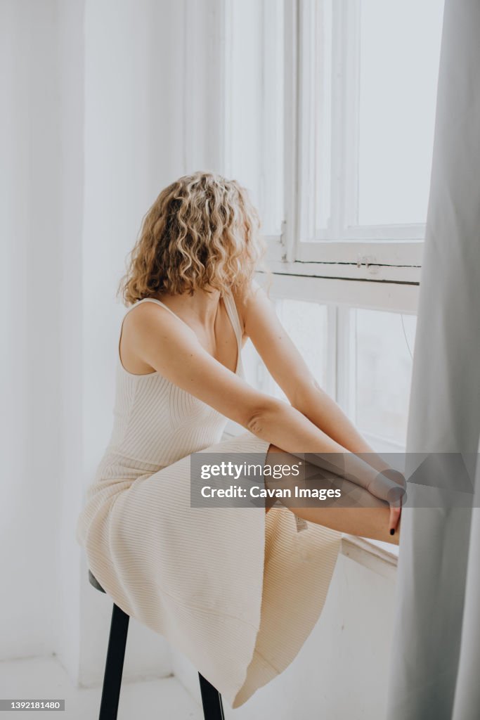 Woman in white dress near window