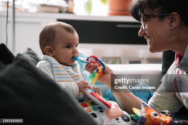 grandmother playing with her baby on the sofa. - gezahnt stock-fotos und bilder