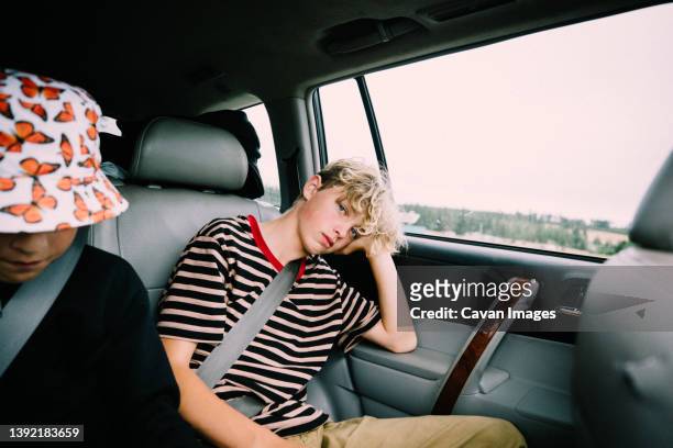 bored kids passing time in the backseat on a road trip - backseat bildbanksfoton och bilder