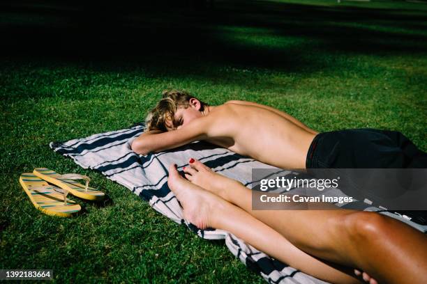 flip flops, teen boy and bare legs on sunny blanket - gebruind stockfoto's en -beelden