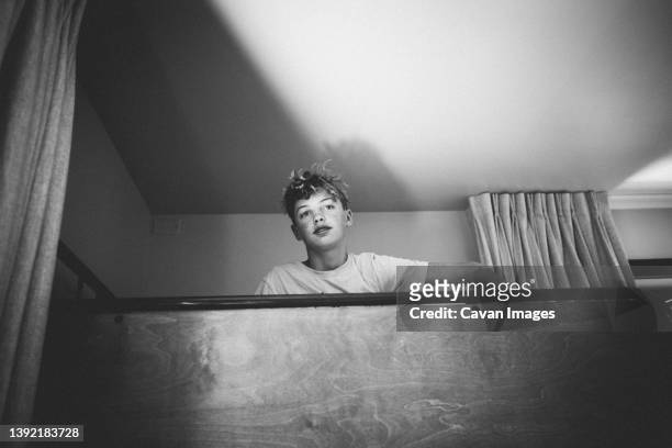 teen boy with messy hair peeks from atop a bunkbed - kids in bunk bed stock pictures, royalty-free photos & images