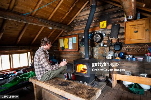 drinking coffee with a fire inside the snow peak cabin - wood burning stove stock pictures, royalty-free photos & images