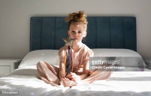 girl sat on a bed with a star and rainbows from the sun - magic wand stock pictures, royalty-free photos & images