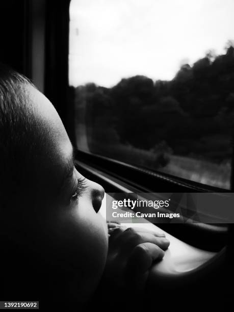 sad little boy looking out the window in the train close-up - rebirth stockfoto's en -beelden