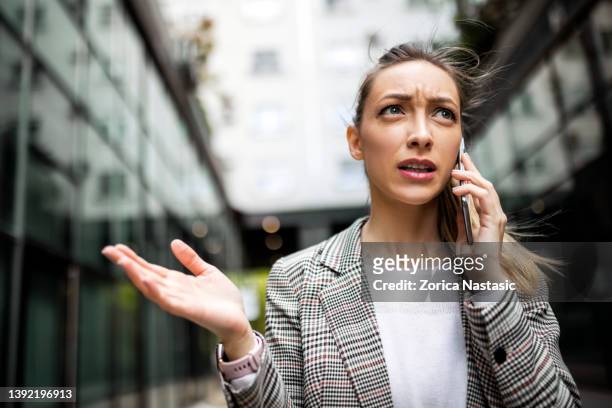 femme d’affaires mécontente utilisant le téléphone - communication problems photos et images de collection