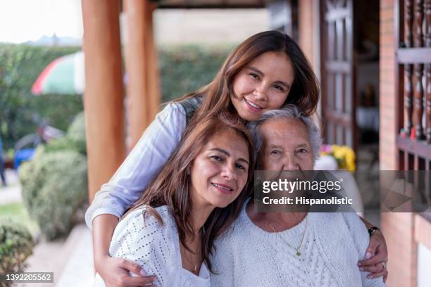 portrait of grandmother, daughter and granddaughter facing camera smiling very cheerfully - multi generation family stockfoto's en -beelden