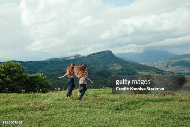 two european young twins run on a green meadow - identical twin stock pictures, royalty-free photos & images