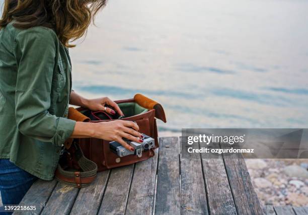 fotografin mit retro-kamera und ledertasche in strandnähe - camera bag stock-fotos und bilder