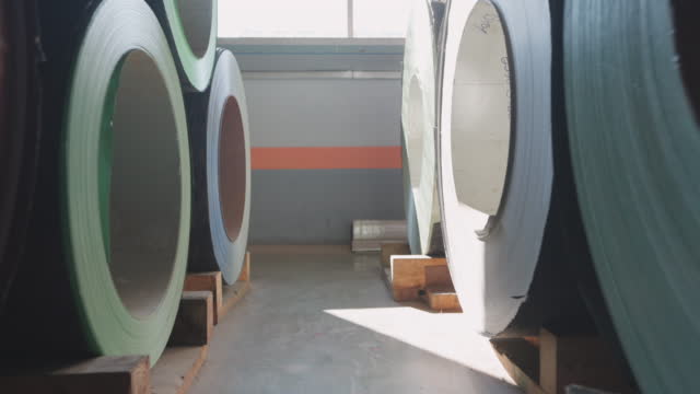 Industrial. Rolled steel. Stack of rolls. Steel sheets rolled up into rolls stacked in layers on the raw material store of the manufacturing plant. Export Steel. Roll of steel sheet or aluminum preparing for the metal part production in heavy factory.