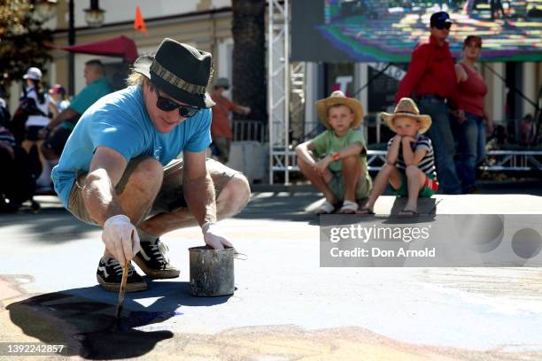 Young boys look as a street artist paints a golden coloured guitar on the road on April 19, 2022 in Tamworth, Australia. The Tamworth Country Music...