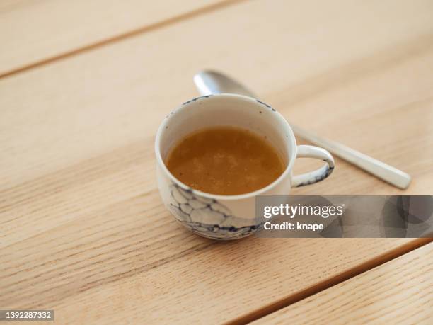 chicken bone broth in a cup with spoon - bone broth stock pictures, royalty-free photos & images