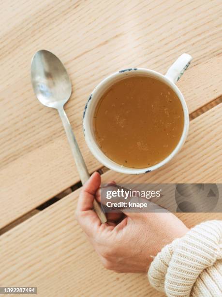 chicken bone broth in a cup with spoon - bone broth stock pictures, royalty-free photos & images