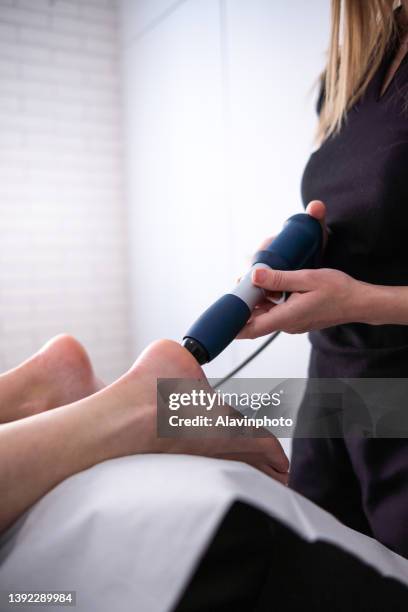 female physiotherapist doing shockwave treatment neurological hammer massage foot massage - shockwave therapy stock pictures, royalty-free photos & images