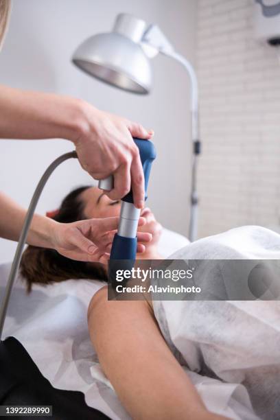 female physiotherapist doing shockwave treatment neurological hammer massage shoulder - shockwave therapy stock-fotos und bilder