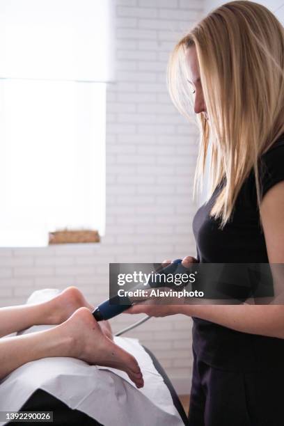 female physiotherapist doing shockwave treatment neurological hammer massage foot massage - shockwave therapy stock pictures, royalty-free photos & images