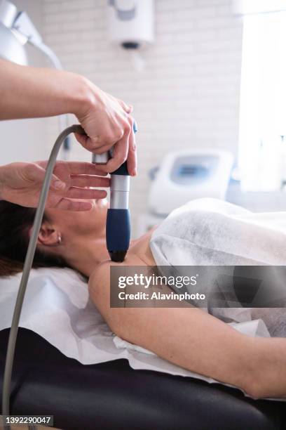 female physiotherapist doing shockwave treatment neurological hammer massage shoulder - shockwave therapy stockfoto's en -beelden