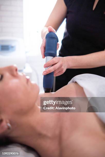 female physiotherapist doing shockwave treatment neurological hammer massage shoulder - shockwave therapy stock pictures, royalty-free photos & images