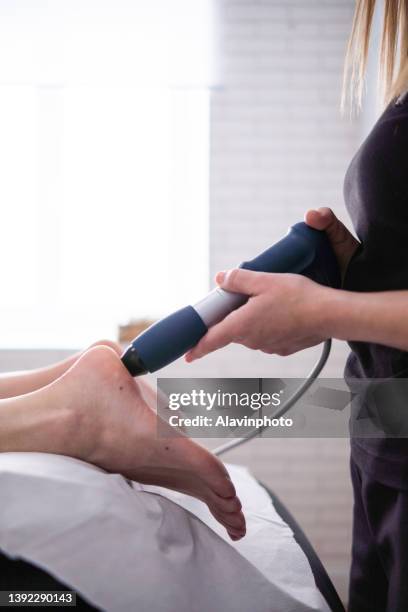 female physiotherapist doing shockwave treatment neurological hammer massage foot massage - shockwave therapy stock pictures, royalty-free photos & images