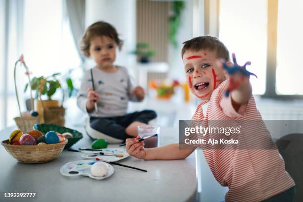 siblings painting easter eggs together. - dirty easter stock pictures, royalty-free photos & images