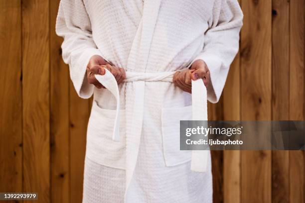 close up on the hands of a man as he is tying the belt of his bathrobe - bathrobe 個照片及圖片檔