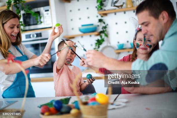 family painting easter eggs together. - dirty easter stock pictures, royalty-free photos & images