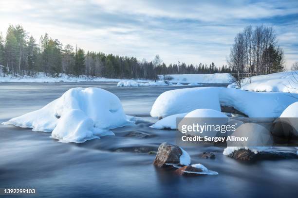 river flowing through snowcapped rocks in winter - cumulo di neve foto e immagini stock