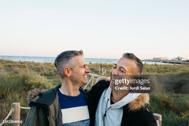 same sex couple on the beach - hispanic gay man stock pictures, royalty-free photos & images