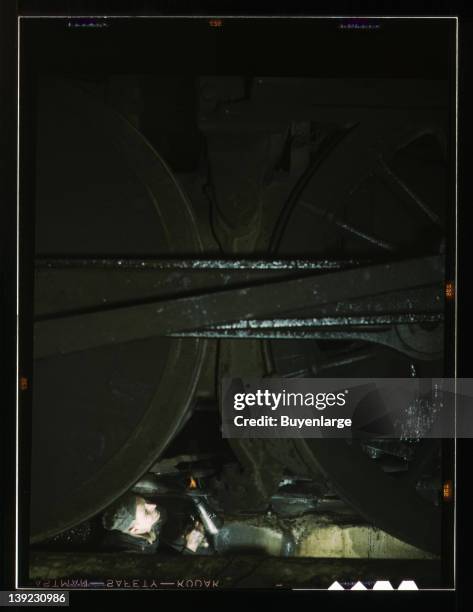 Worker inspecting a locomotive on a pit in the roundhouse at the Chicago & Northwestern Railroad Proviso yard, Chicago, Illinois, 1942.