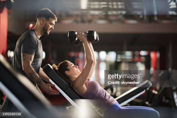young man helping his girlfriend during her sports training in a health club. - gym stockfoto's en -beelden