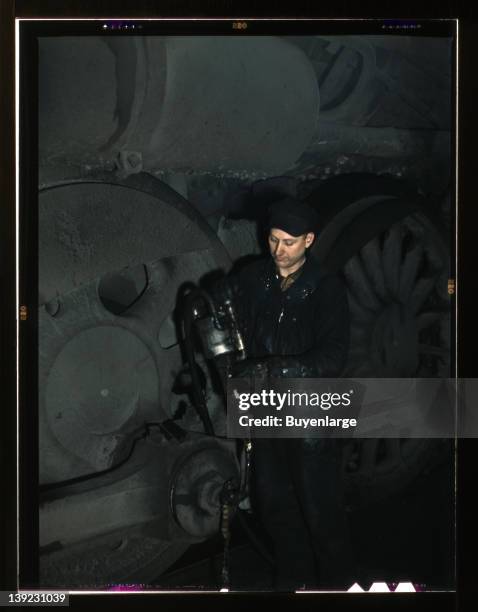Greasing a locomotive in the roundhouse at Proviso yard, Chicago & Northwestern Railroad, Chicago, Illinois, 1942.