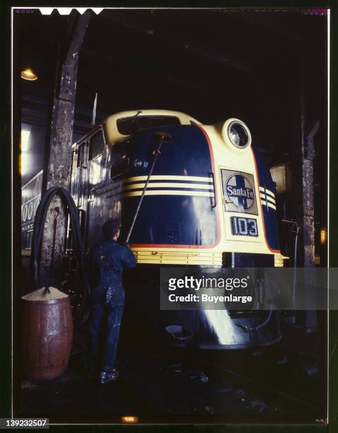 Washing one of the Santa Fe Railroad's 54 hundred horse power diesel freight locomotives in the roundhouse at the Argentine yard, Kansas City,...