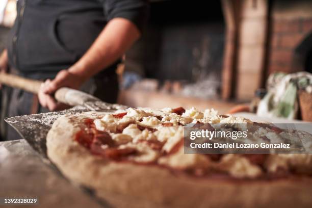 crop man preparing traditional pizza in restaurant - pizzeria stockfoto's en -beelden