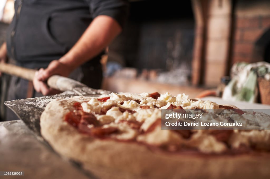 Crop man preparing traditional pizza in restaurant