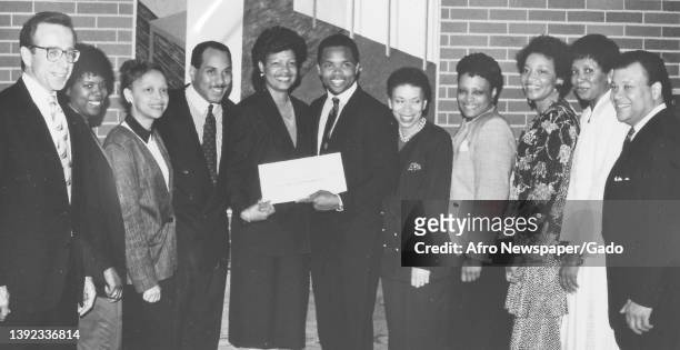 Group shot of smiling former politician Jesse Jackson Jr and McDonald's employees, presenting an oversized donation cheque to United Negro College...