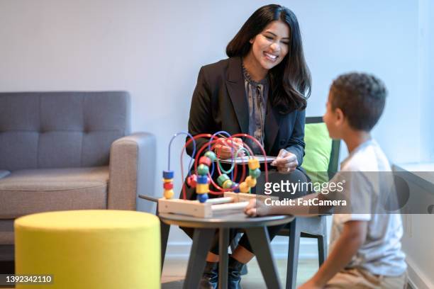 therapist playing with young patient - arabic doctor stockfoto's en -beelden