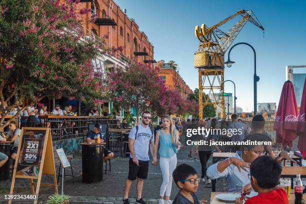 die uferpromenade von puerto madero in buenos aires, argentinien. die ehemaligen lagerhäuser wurden in wohnungen mit cafés und restaurants im sockel umgewandelt. - puerto madero stock-fotos und bilder