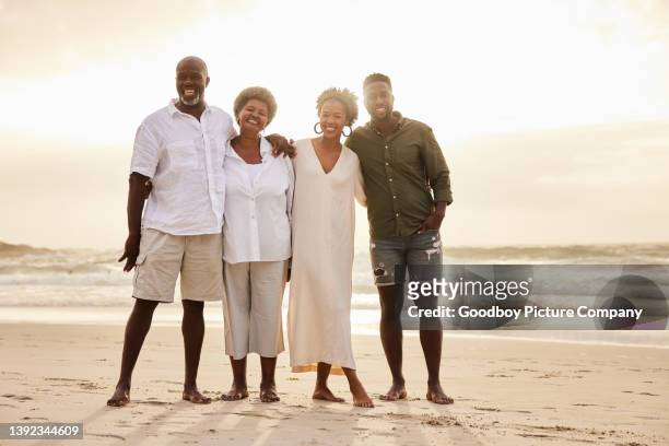 young couple and their senior parents smiling together on a beach - family trip in laws stock pictures, royalty-free photos & images