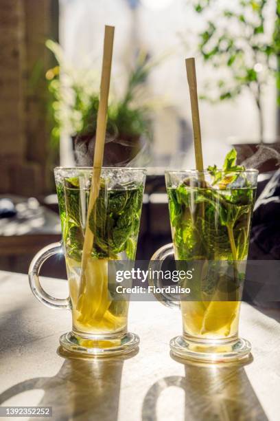 glass bottle for a drink with a paper straw on sunny background - lemongrass stockfoto's en -beelden