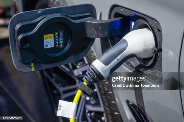 close up of the power supply plugged into an electric car being charged. - charge stockfoto's en -beelden