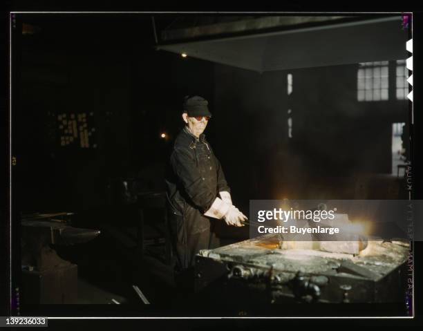 Blacksmith, at his forge in the blacksmith shop at the roundhouse, 1943.