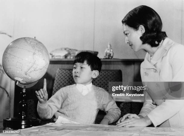 Prince Hiro, aka Crown Prince Naruhito of Japan, studying a globe with his mother, Empress Michiko, at Togu Palace in Tokyo, February 1968. The globe...